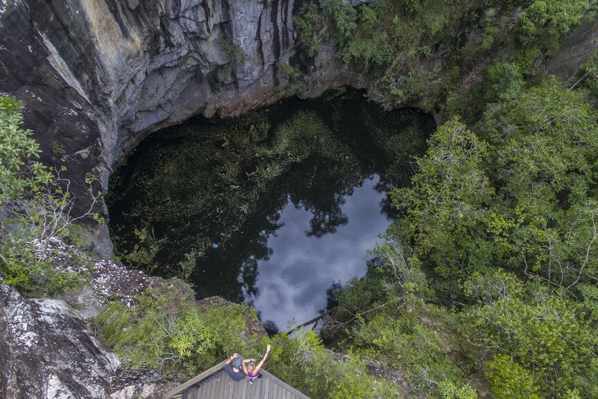 Looking down into a large crater filled with greenish water