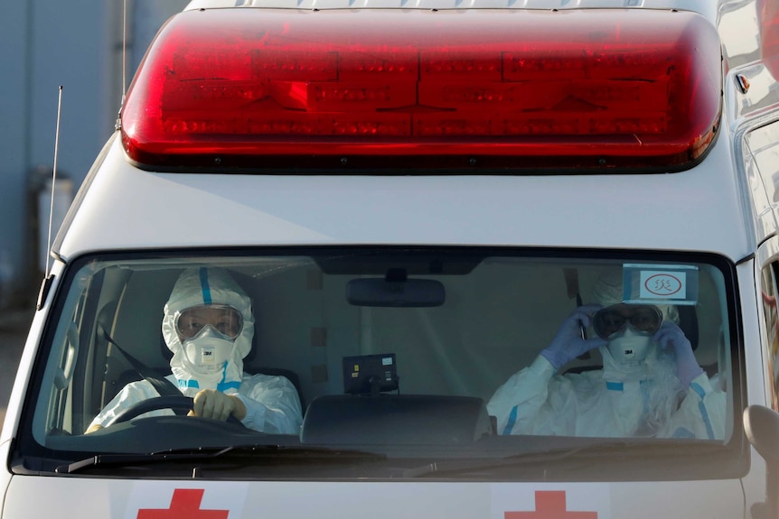 Two people in hazmat suits in an ambulance