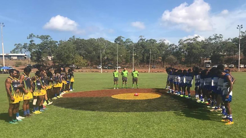 Two teams standing on opposite sides of the oval on Yirrkala final day.