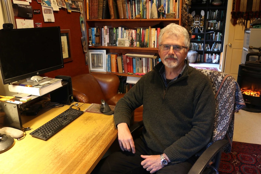 A man sitting at a desk surrounded by books.