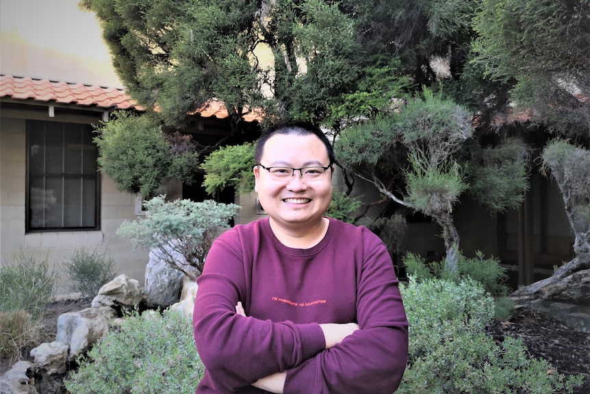 Yu Tao stands in a garden posing for a photo. 