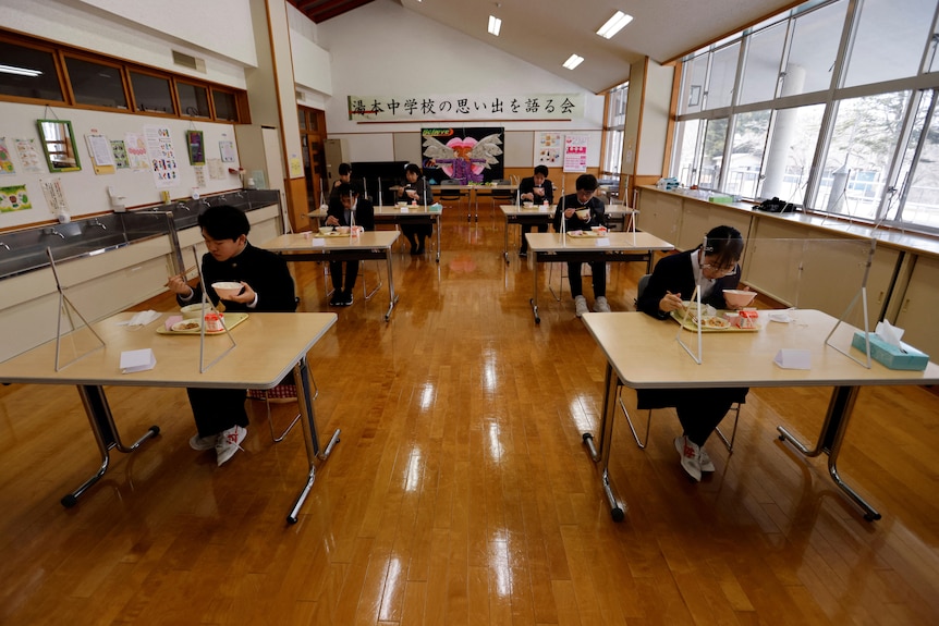Eita Sato and Aoi Hoshi sit at their desks and eat lunch as do their school teachers in the same school room