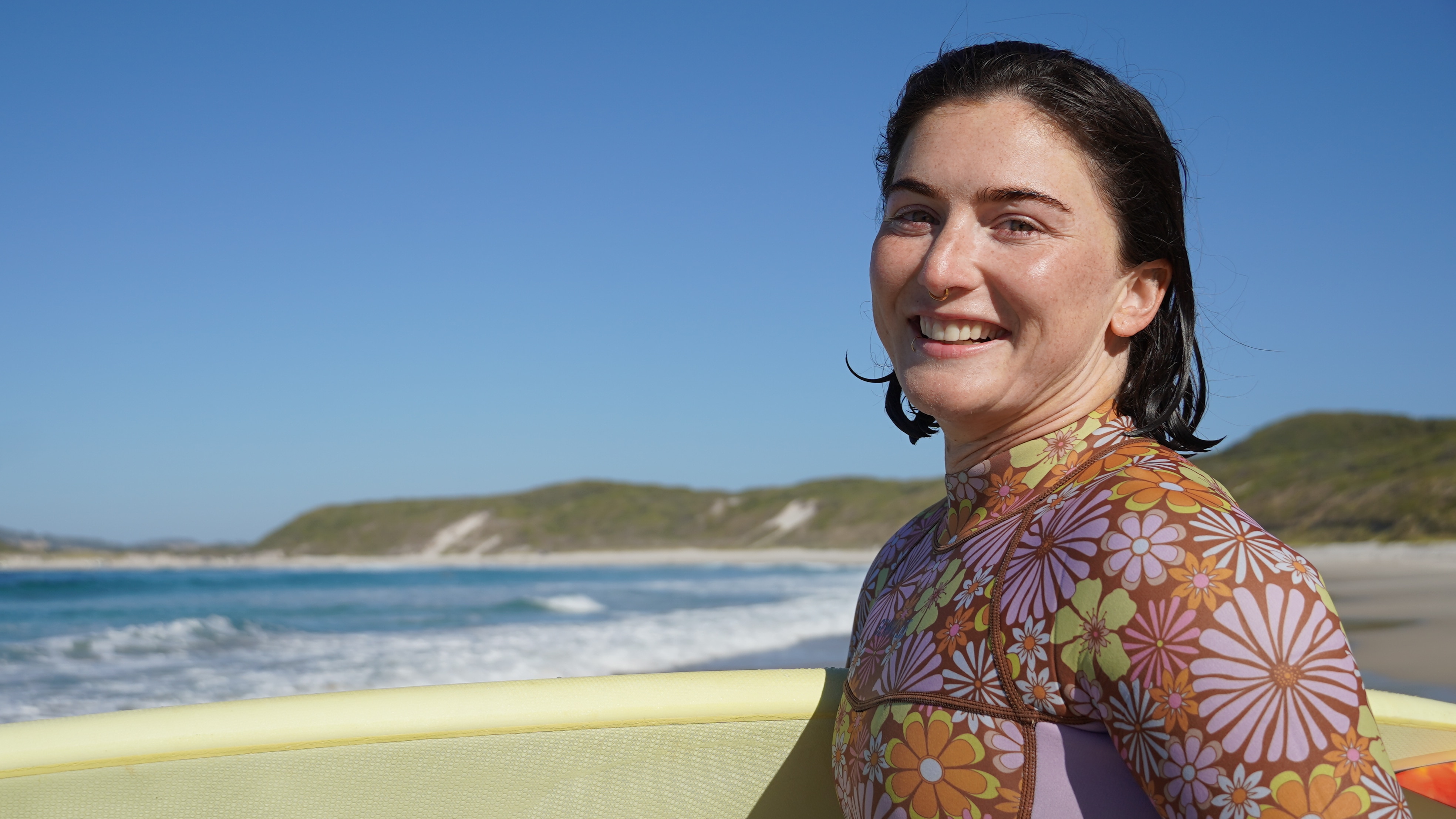 Monique Blaikie lleva su tabla por la playa. 