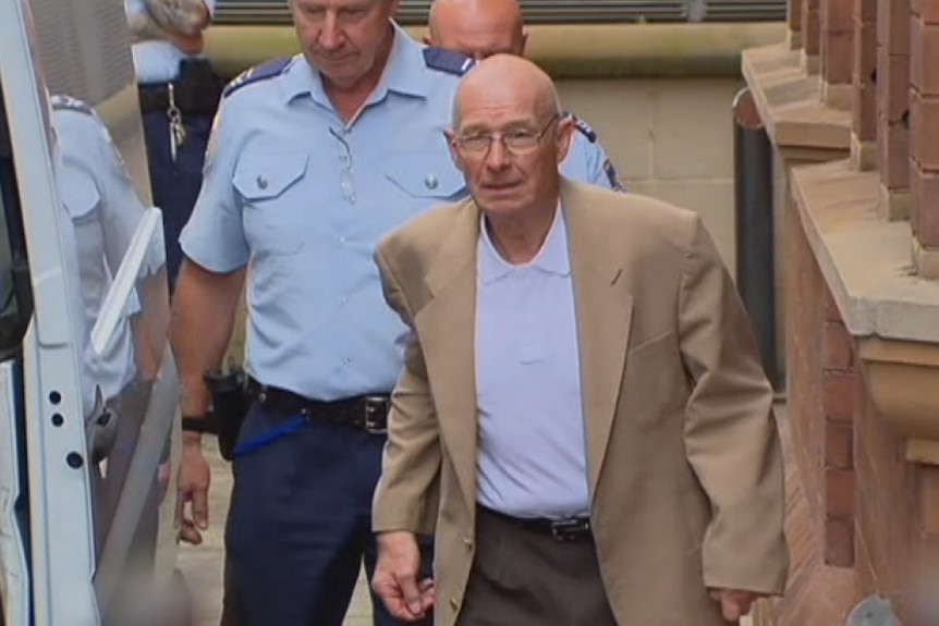 Roger Rogerson arrives at the NSW Supreme Court lead by a police guard.