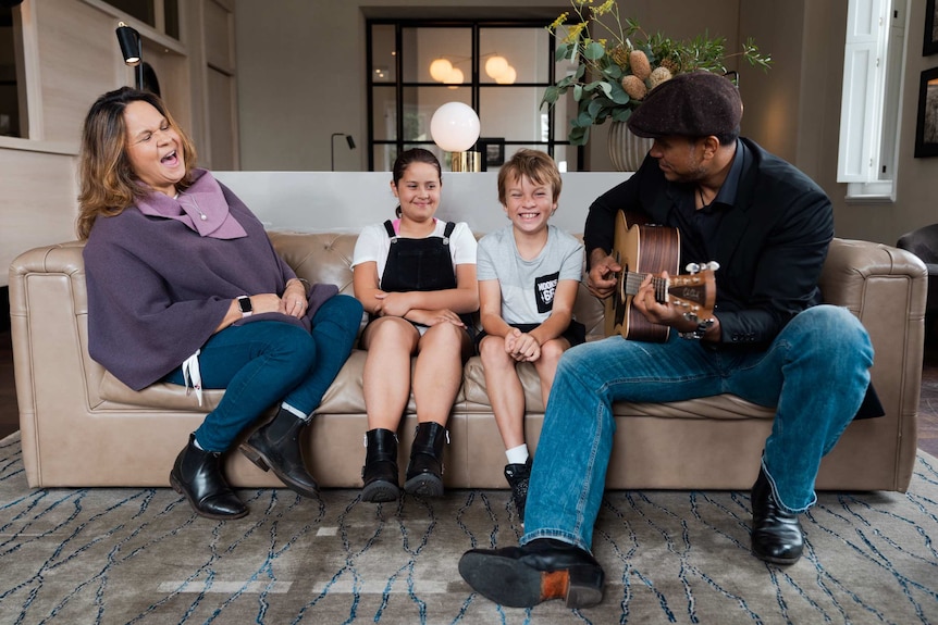 Gina Williams and Guy Ghouse sitting on a couch singing with two children