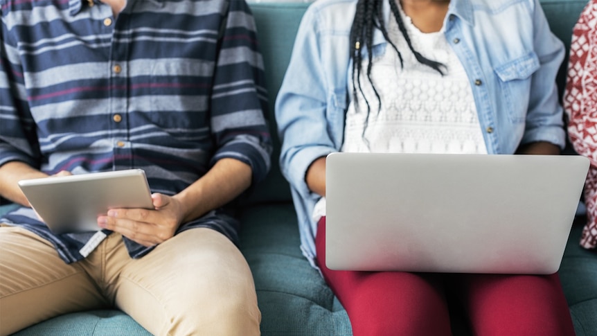 Young people using a laptop computer and tablet.