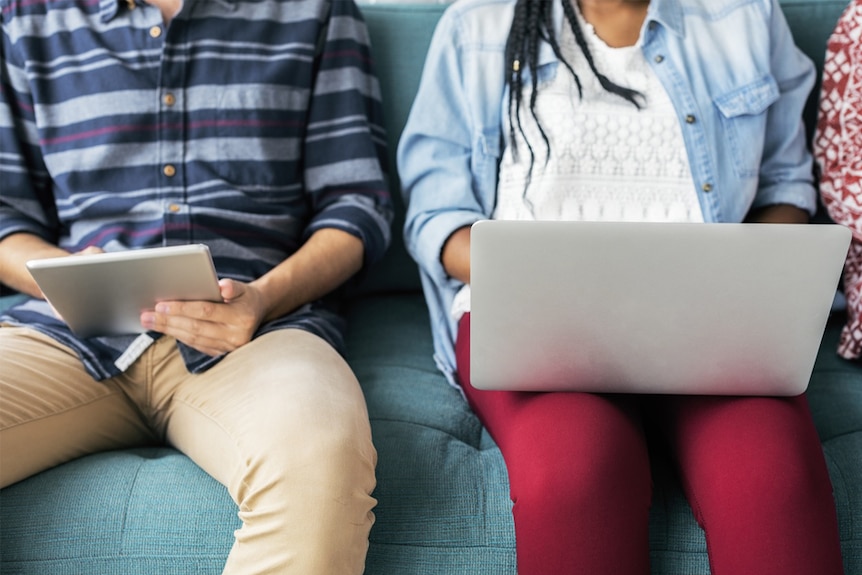 Young people using a laptop computer and tablet.