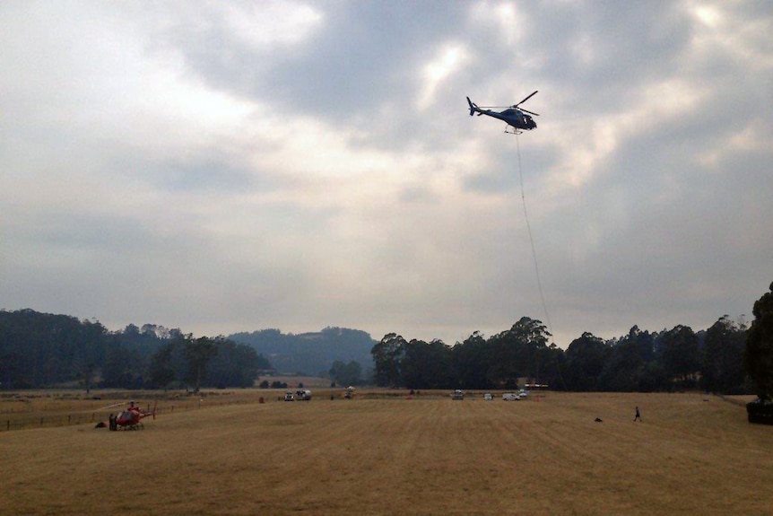A water-bombing helicopter takes to the sky to tackle remote bushfires in Tasmania.