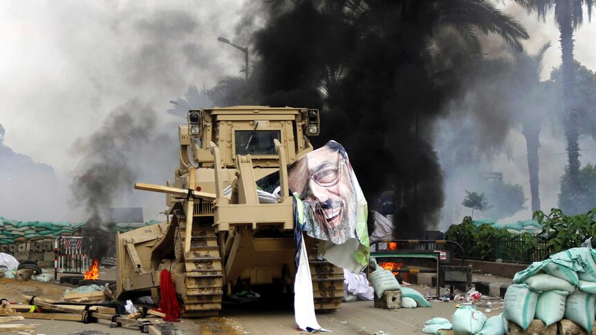 A torn poster of deposed Egyptian President Mohammed Morsi hangs from an armoured bulldozer.