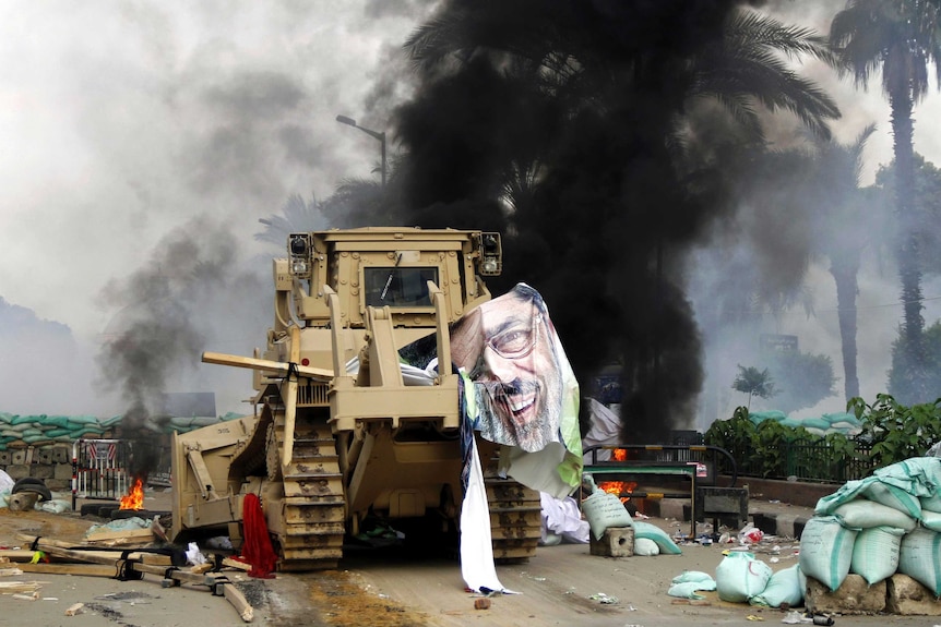 A torn poster of deposed Egyptian President Mohammed Morsi hangs from an armoured bulldozer.