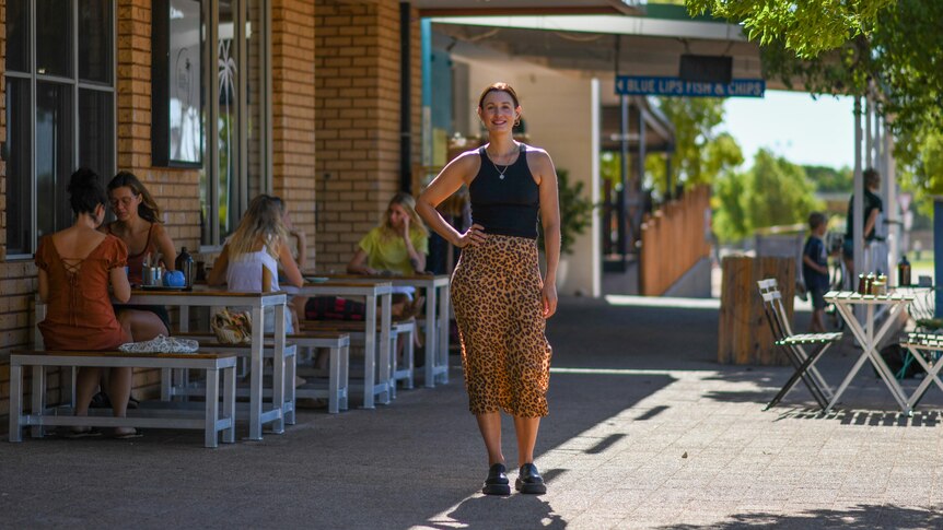 A smiling woman stands outside a cafe in Exmouth