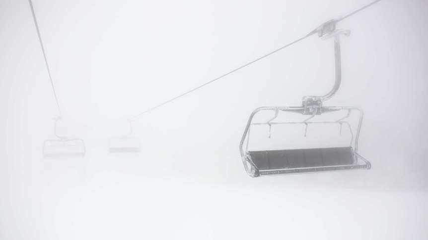 Ice crusts a chairlift as it disappears into the mist.