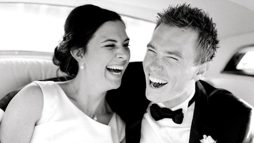 A black and white bride and groom photo with the couple ecstatically laughing