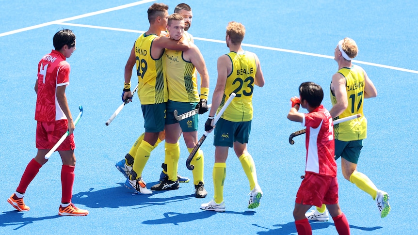 Hockey players hugging in celebration after getting a goal during a match