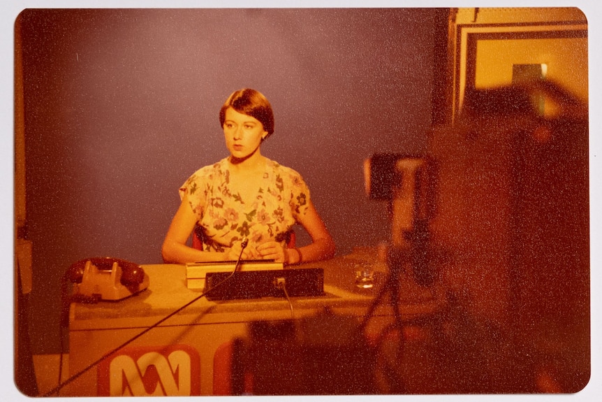 An historical photo of a female ABC Darwin TV presenter. She has short hair and is wearing a floral dress.