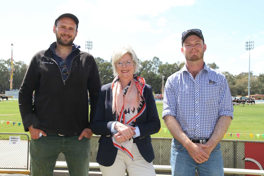 A woman stands between two men.