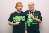 Ed Sheeran points at Michael Gudinski who hugs him and points a finger up. They wear matching black t shirts