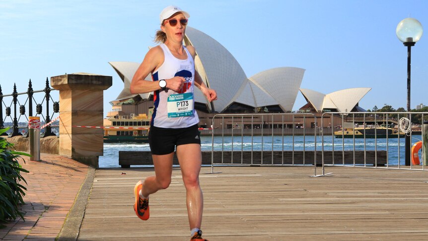 An action shot of Regina running. Behind her is the Sydney Opera House