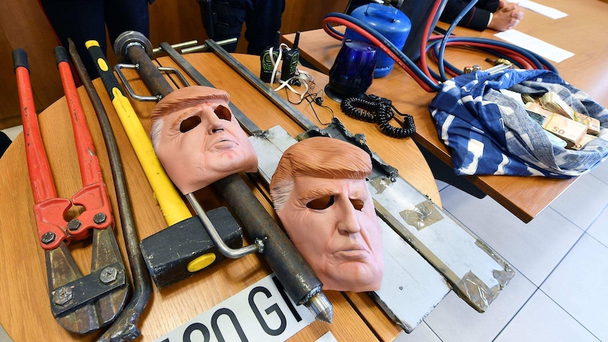 A number of tools, Donald Trump masks and cash are displayed on a table.
