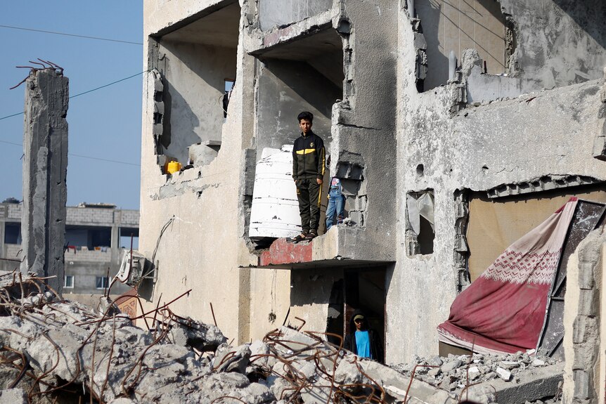 Boy stands in building partially destroyed and crumbled 