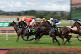 Horses running around a racecourse. 