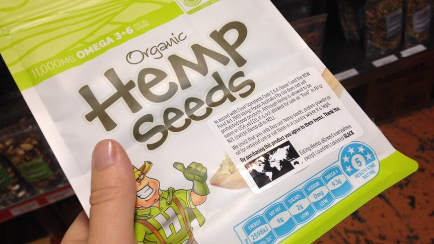 A consumer holding a packet of organic hemp seeds in a health food store.