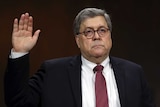 US Attorney General William Barr swearing to testify with one hand up in the air.