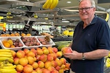 Scott Ledger holding a mango in a supermarket