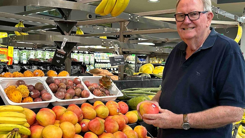 Scott Ledger holding a mango in a supermarket