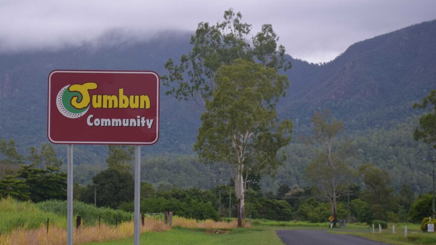 A sign that reads Jumbun Community surrounded by misty skies and vivid green grass