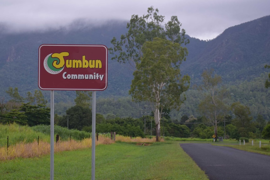 A sign that reads Jumbun Community surrounded by misty skies and vivid green grass