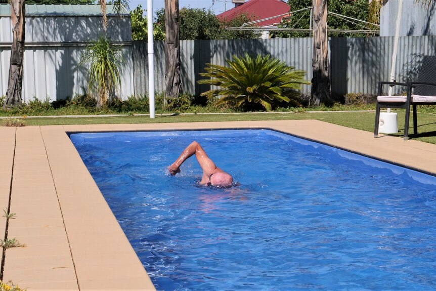 Man swimming in backyard outdoor pool