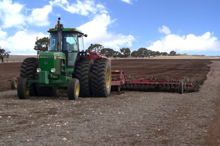 A tractor ploughs a paddock after rain.