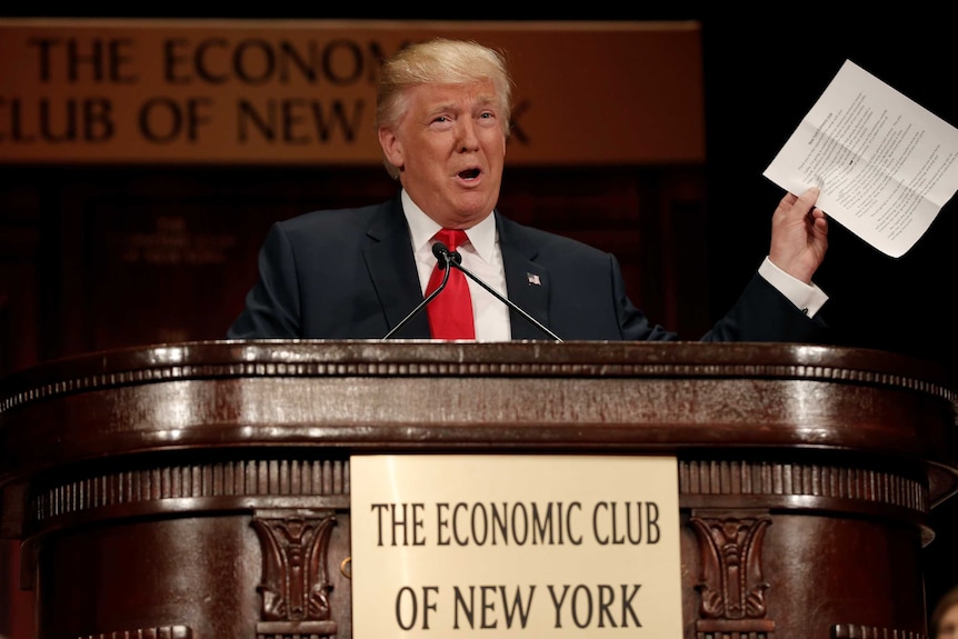 Donald Trump holds up piece of paper as he speaks in New York.