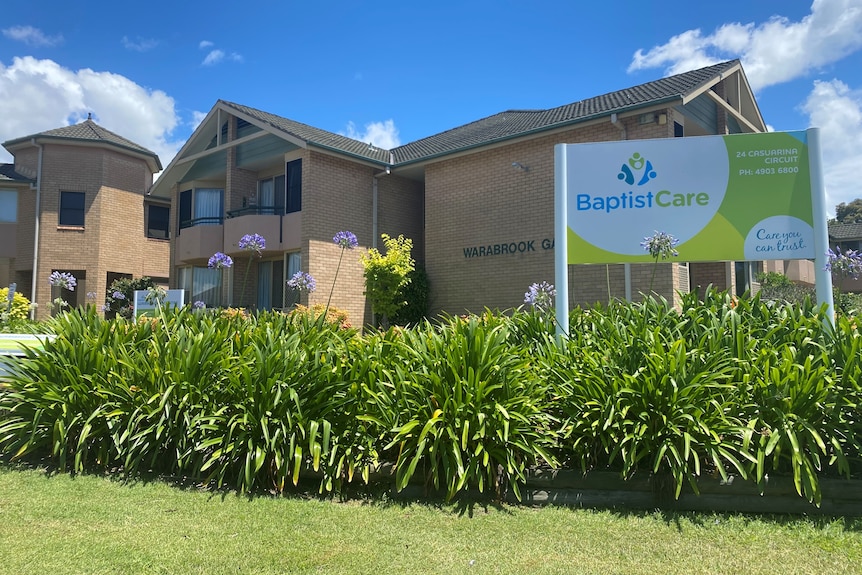 A large residential brick building, with a white and green sign at the front reading BaptistCare.