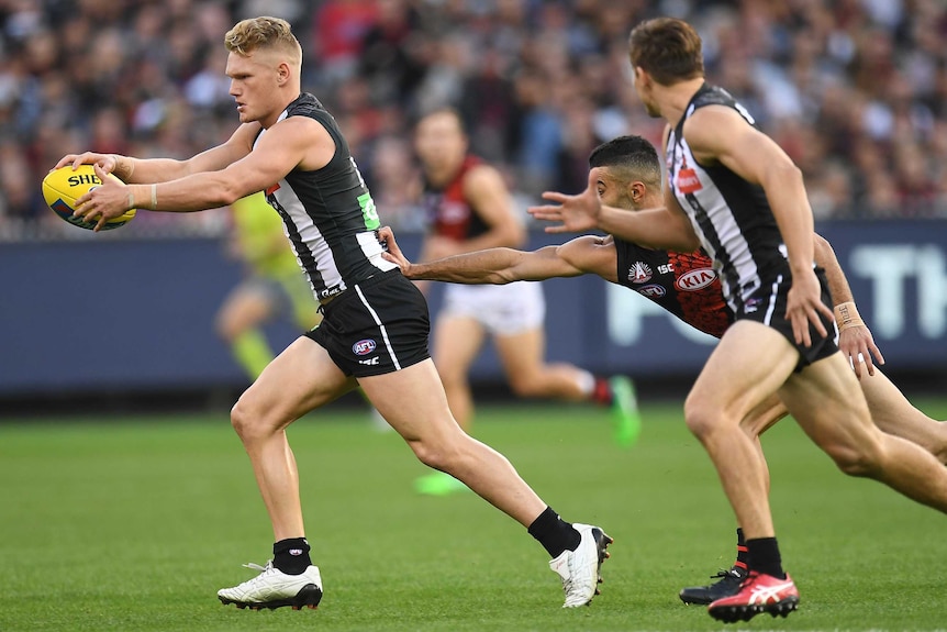 Adam Treloar evades a tackler