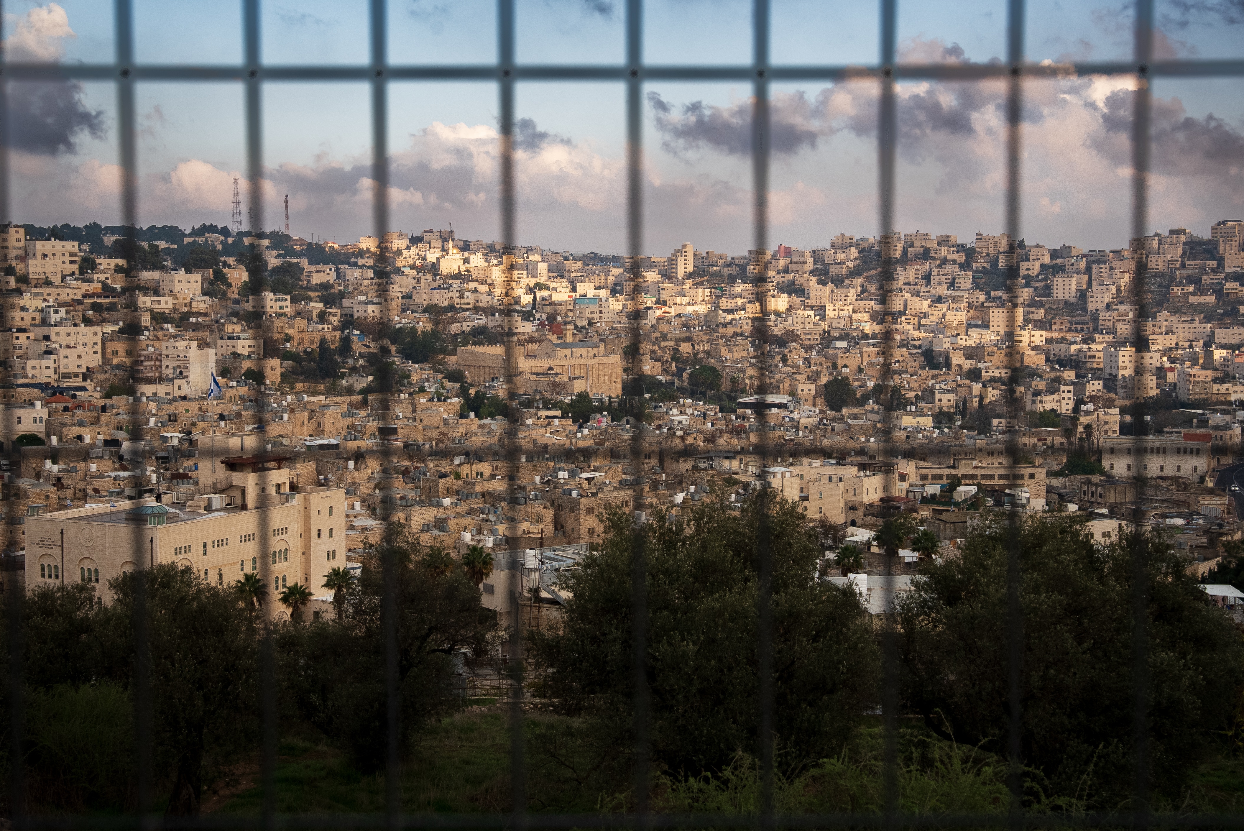 A valley with hundreds of buildings in the distance behind a fence