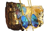 Two opal earrings sitting on a raw opal