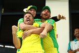 Three Australian cricketers embrace after their team wins the T20 World Cup final.