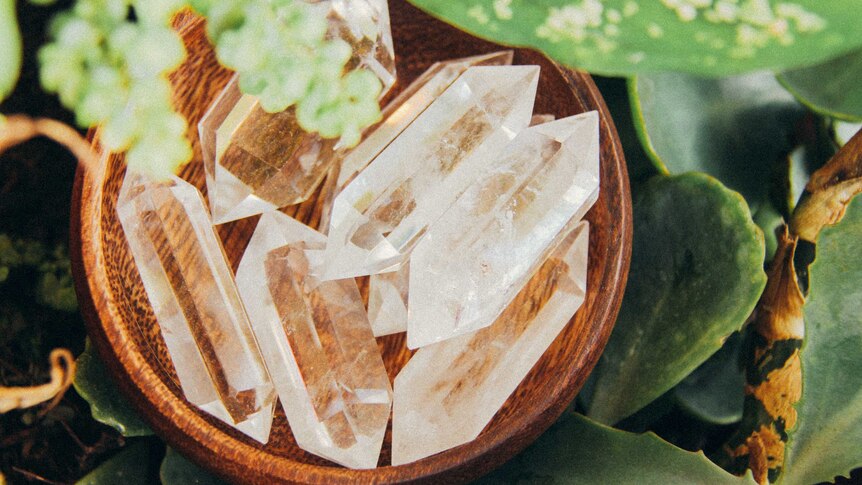A small wooden bowl containing clear prism-shaped crystals