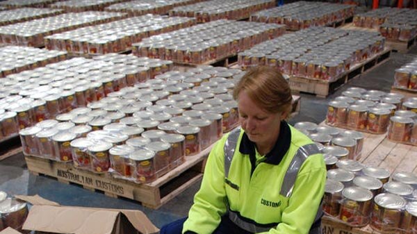 Customs officer unpacking cans allegedly containing ecstasy.