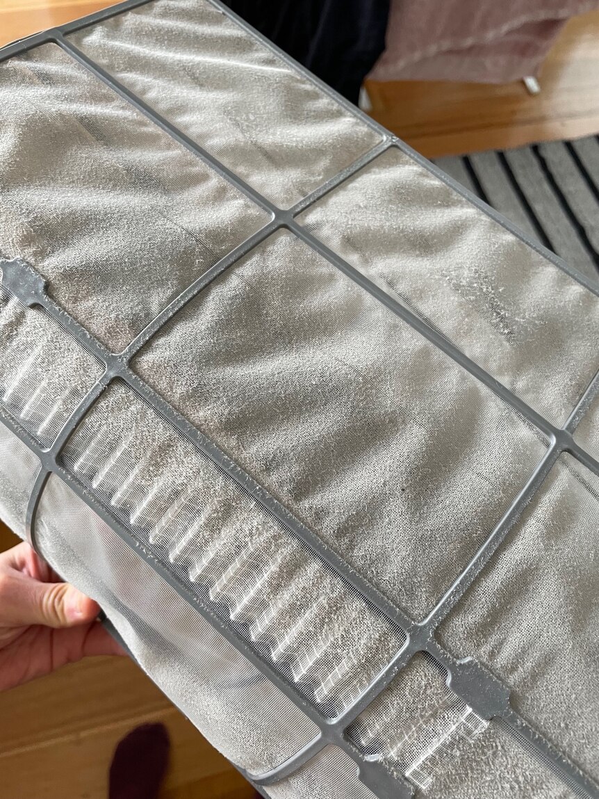 A filter panel from a reverse-cycle air-conditioner covered in dust, cleaning will help efficiency and heat.