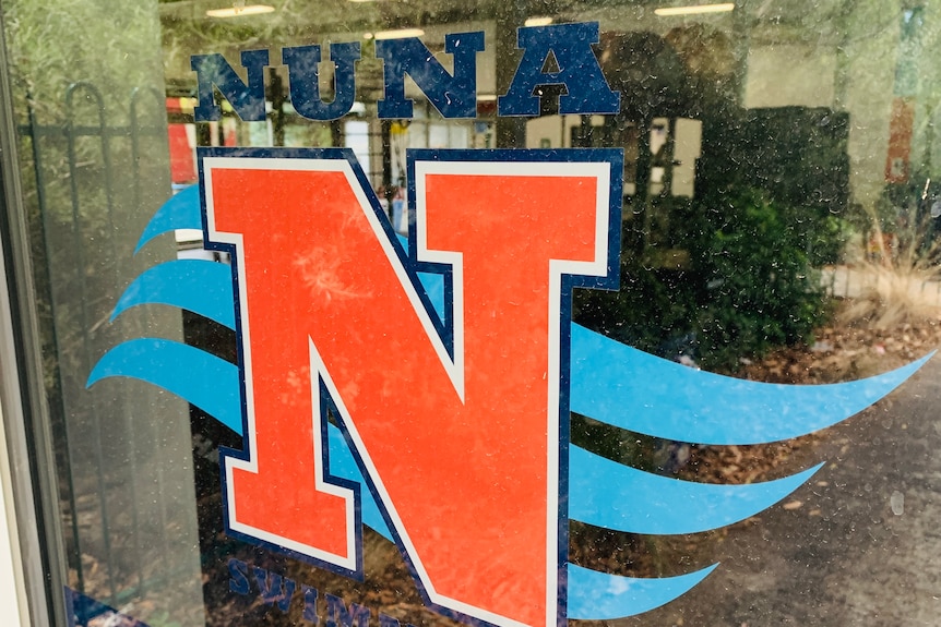 A large red letter N can be seen on a window of a swimming club.