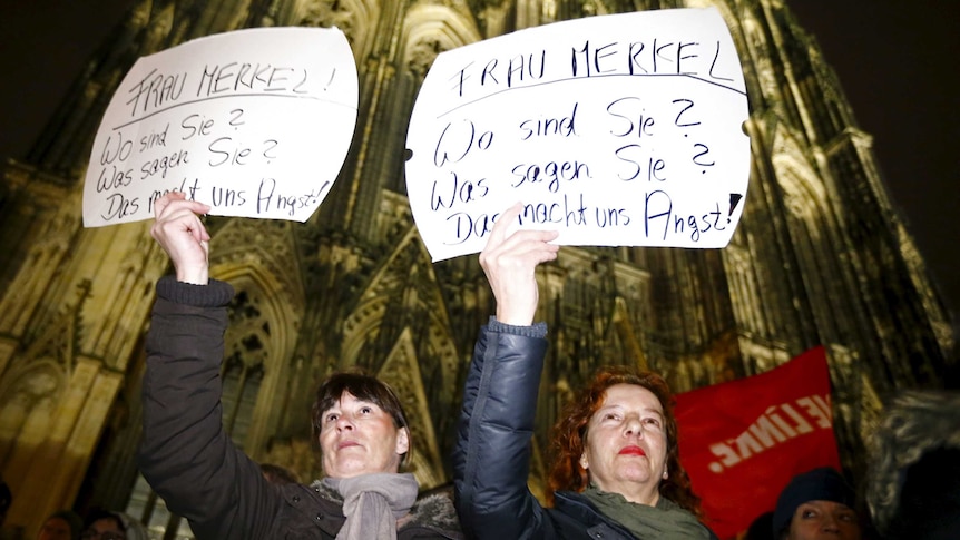 Women hold up placards during a protest in front of the Cologne Cathedral