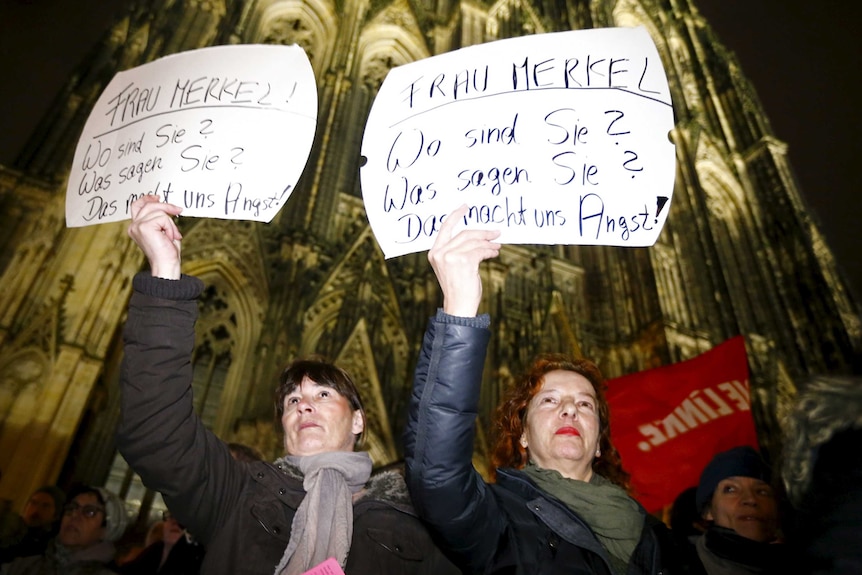 Women hold up placards during a protest in front of the Cologne Cathedral