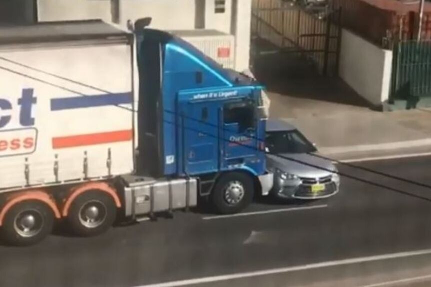 A massive truck nudging a car.