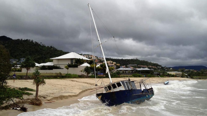 Waves wash over a grounded yacht in Cannonvale