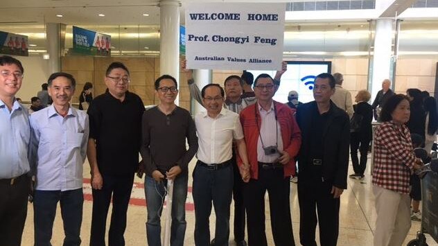 Professor Feng Chongyi is surrounded by people holding a sign reading: "Welcome home Prof. Chongyi Feng."
