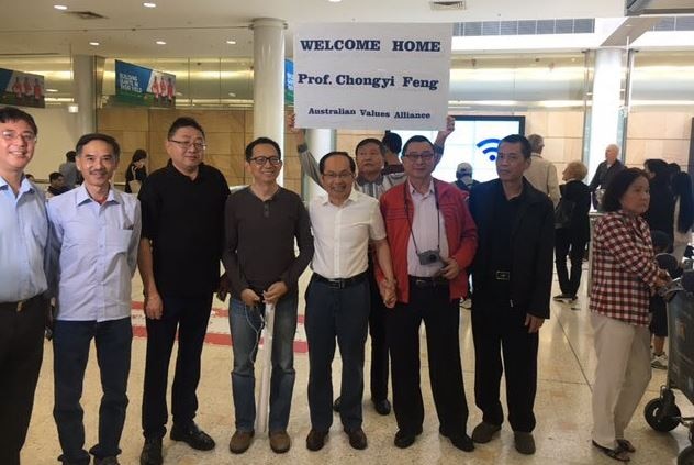 Professor Feng Chongyi is surrounded by people holding a sign reading: "Welcome home Prof. Chongyi Feng."