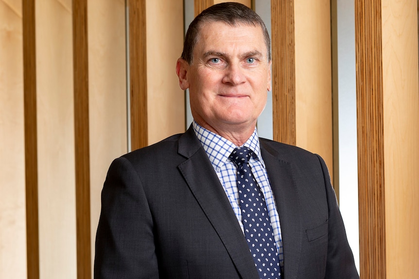 Man in suit stands smiling in an office